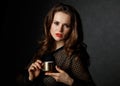 Portrait of woman holding cup of coffee against dark background Royalty Free Stock Photo