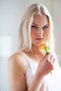 Portrait, woman and holding of flower in bedroom for romance with headshot in Norway. Female person, looking and hand