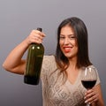 Portrait of woman holding wine bottle and glass against gray background