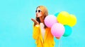 Portrait woman holds balloons sends an air kiss in yellow coat Royalty Free Stock Photo