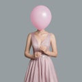 woman im evening dress. Hides her face behind pink balloon