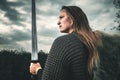 Portrait of woman in image of medieval warrior under dramatic sky