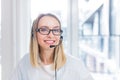 Portrait of a woman looking at the camera, young blonde woman with headset and glasses communicates with customers Royalty Free Stock Photo