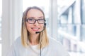 Portrait of a woman looking at the camera, young blonde woman with headset and glasses communicates with customers Royalty Free Stock Photo