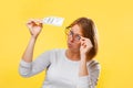 Portrait of woman looking at the dollar bill checking for falsity. Yellow background. The concept of checking counterfeit money Royalty Free Stock Photo