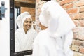 Portrait of beautiful woman looking into mirror in bathroom applying cream on face, healthy grooming skin care cosmetics