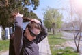 Portrait of woman makes ponytail walking in city park, she does her hairs.