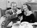 Portrait of a woman and a man feeding soup to each other at a table