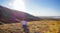 Portrait of a woman meditative practice sitting on the ground in the Lotus position and looking into the distance at the field,