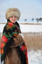 The portrait of the woman of middle age in a fur cap and a colorful shawl costs against the winter lake Royalty Free Stock Photo