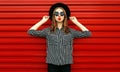 Portrait woman model wearing a black white striped shirt, round hat posing on city street over red wall Royalty Free Stock Photo