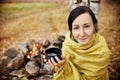 Portrait of a woman with a mug of hot tea in his hands autumn in a forest campfire. A picnic in the autumn forest. Girl wrapped Royalty Free Stock Photo