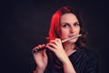 Portrait of a woman musician with a piccolo flute on a studio black background. Flutist with a small flute in her hands Royalty Free Stock Photo