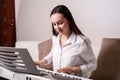 Portrait of a woman passionate about learning to play the electronic piano in the interior of the apartment