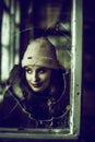 Portrait of a woman photographed through broken glass of a window.Urban exploration concept. Royalty Free Stock Photo