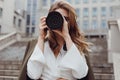 Portrait of woman photographer covering her face with camera outdoors Royalty Free Stock Photo