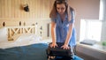 Portrait of young woman puching lid of suitcase trying to close it