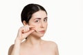 Portrait of a woman pulling the skin on her face with her fingers. White background. Copy space. The concept of anti-aging care Royalty Free Stock Photo