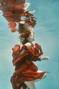 Portrait of a woman in a red dress floating underwater