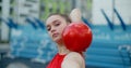 Portrait of woman in red sports costume performing callisthenics exercises with gymnastic ball outdoors, sports in the