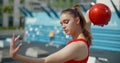 Portrait of woman in red sports costume performing callisthenics exercises with gymnastic ball outdoors, sports in the