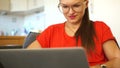 Portrait of a woman in red working behind a laptop monitor. Meiling, woman freelancer, secretary, office employee
