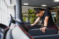 Portrait of a woman resting after her workout. She is leaning on a treadmill and looks completely exhuasted