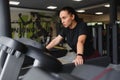 Portrait of a woman resting after her workout. She is leaning on a treadmill and looks completely exhuasted