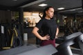 Portrait of a woman resting after her workout. She is leaning on a treadmill and looks completely exhuasted