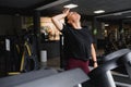 Portrait of a woman resting after her workout. She is leaning on a treadmill and looks completely exhuasted