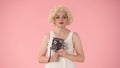 Portrait of woman with retro video camera in hands close up. Woman looking like Marilyn Monroe in studio on pink Royalty Free Stock Photo