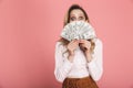 Portrait of woman 30s in trendy wear hiding while holding money fan isolated over pink background Royalty Free Stock Photo