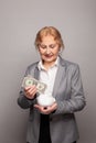 Portrait of woman 60 years old holding US dollars and piggy bank Royalty Free Stock Photo