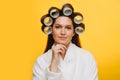 Portrait of a woman sitting with hair in rollers supporting chin with fingers Royalty Free Stock Photo