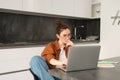Portrait of woman sitting at home with laptop. Businesswoman managing her own business remotely from her kitchen