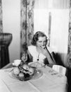 Portrait of a woman sitting at a table and eating a piece of bread Royalty Free Stock Photo