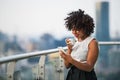 A portrait of a woman with smartphone standing on a terrace, drinking coffee. Royalty Free Stock Photo
