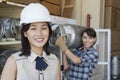 Portrait of woman smiling with female industrial worker carrying propane cylinder in background