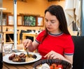 Portrait of woman spending time on open terrace of restaurant and eating traditional parillada de carne