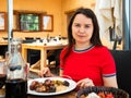Portrait of woman spending time on open terrace of restaurant and eating traditional parillada de carne