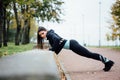 Portrait of woman in sportswear, doing fitness push-ups exercise at fall park, outdoor. Royalty Free Stock Photo