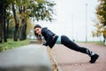 Portrait of woman in sportswear, doing fitness push-ups exercise at fall park, outdoor. Royalty Free Stock Photo