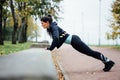 Portrait of woman in sportswear, doing fitness push-ups exercise at fall park, outdoor. Royalty Free Stock Photo