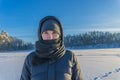 Portrait of a woman standing on frozen lake on a frosty sunny day against the background of a forest