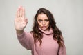 Portrait of a serious young woman standing with outstretched hand showing stop gesture isolated over white background Royalty Free Stock Photo