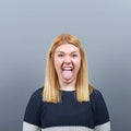 Portrait of woman sticking out her tongue against gray background Royalty Free Stock Photo