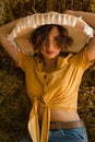 Portrait of a woman with a straw hat sitting in a hayloft