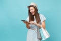 Portrait of woman in summer dress, straw hat holding packages bags with purchases after online shopping, using tablet pc Royalty Free Stock Photo