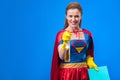 portrait of woman in superhero costume and rubber gloves with rag and detergent