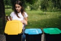 Portrait woman throwing empty plastic water bottle in recycling bin. Tree recycling bins outdoors Royalty Free Stock Photo